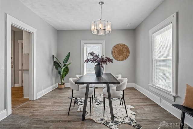 dining area featuring a chandelier, dark wood-style flooring, and baseboards