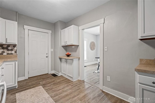 kitchen with wood finished floors, white cabinetry, and baseboards