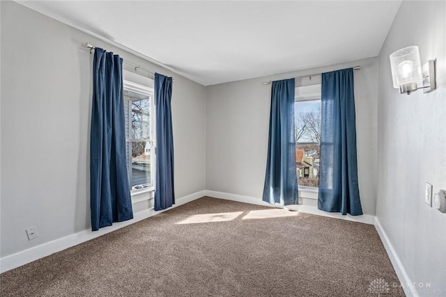 carpeted spare room featuring a wealth of natural light and baseboards