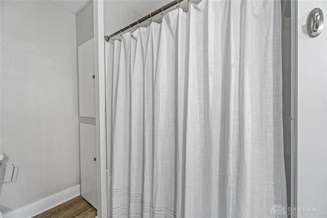 full bathroom featuring wood finished floors and baseboards