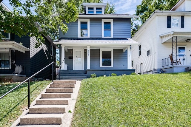 american foursquare style home with a shingled roof, covered porch, and a front lawn