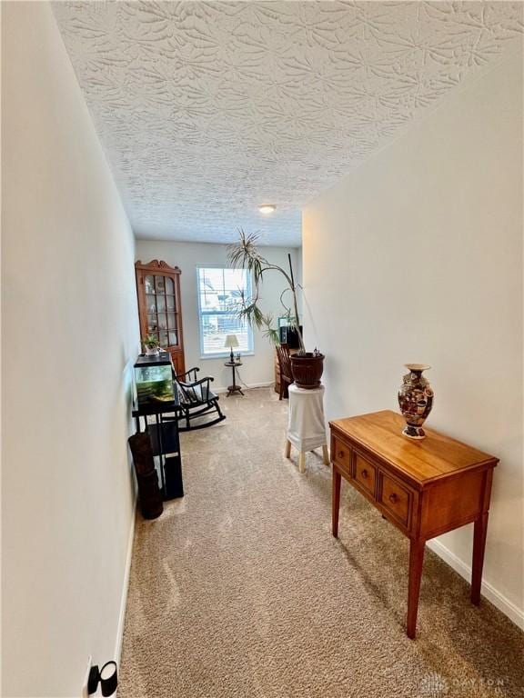 corridor featuring carpet, baseboards, and a textured ceiling