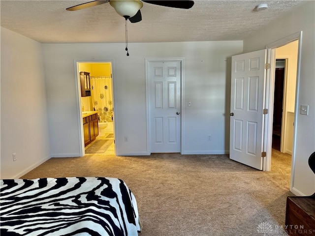 bedroom featuring baseboards, ensuite bathroom, a textured ceiling, and light colored carpet