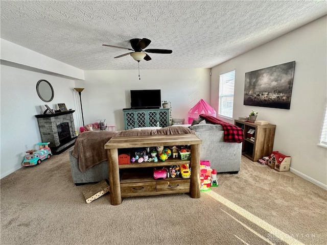 carpeted living area featuring a fireplace, a textured ceiling, baseboards, and ceiling fan