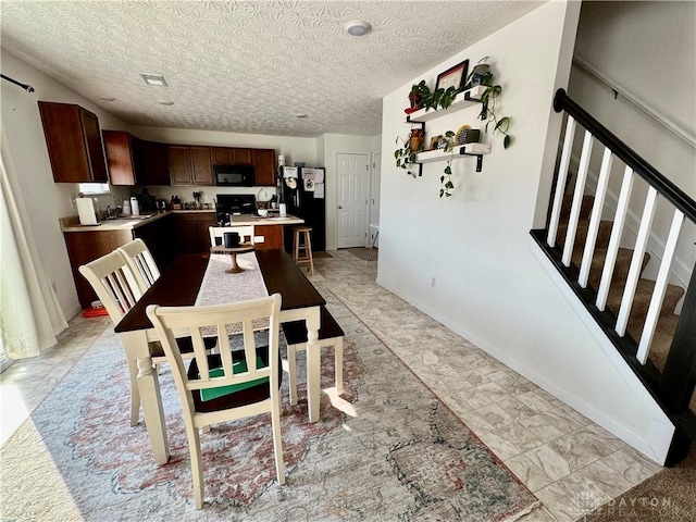 dining space featuring stairway, baseboards, visible vents, and a textured ceiling