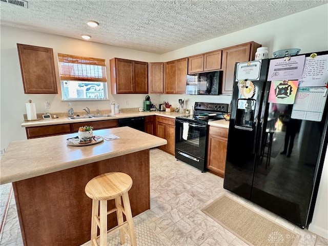 kitchen featuring a breakfast bar, light countertops, a kitchen island, a sink, and black appliances