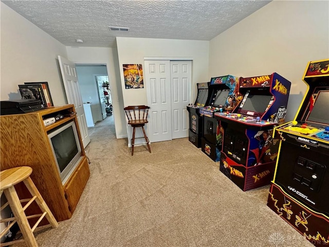 recreation room featuring carpet floors, visible vents, and a textured ceiling