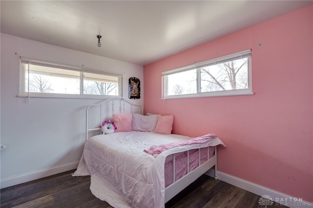 bedroom featuring multiple windows, baseboards, and wood finished floors