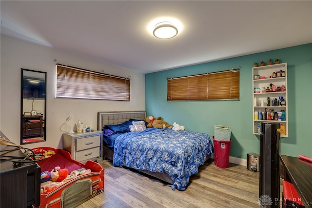 bedroom featuring light wood finished floors and baseboards