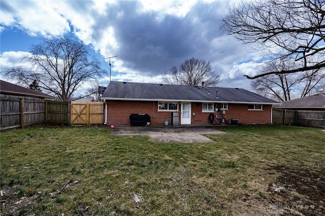 rear view of house with a patio, a fenced backyard, brick siding, a lawn, and a gate