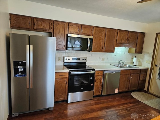 kitchen with stainless steel appliances, dark wood finished floors, light countertops, and a sink