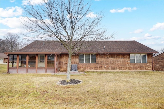 rear view of house with a yard, brick siding, a shingled roof, and a sunroom