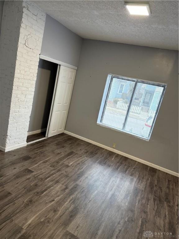 unfurnished bedroom with a closet, baseboards, dark wood finished floors, and a textured ceiling