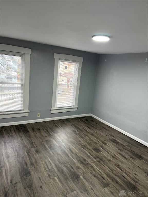 empty room with dark wood-style floors and baseboards