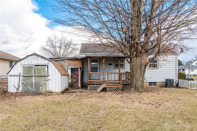 rear view of house featuring a storage shed, an outbuilding, fence, a yard, and central AC