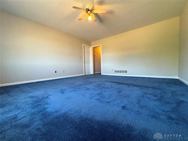 empty room featuring dark carpet, baseboards, visible vents, and ceiling fan