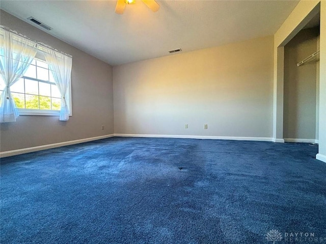 unfurnished room with carpet, visible vents, and a ceiling fan