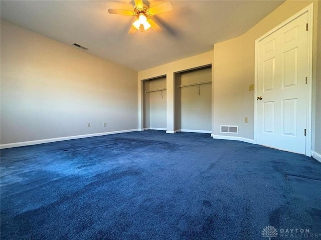 unfurnished bedroom with multiple closets, dark colored carpet, visible vents, and baseboards