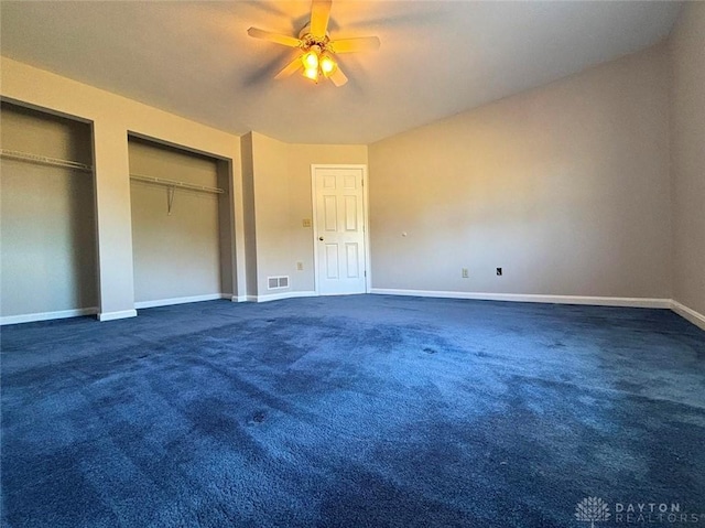 unfurnished bedroom featuring carpet floors, a ceiling fan, visible vents, baseboards, and two closets