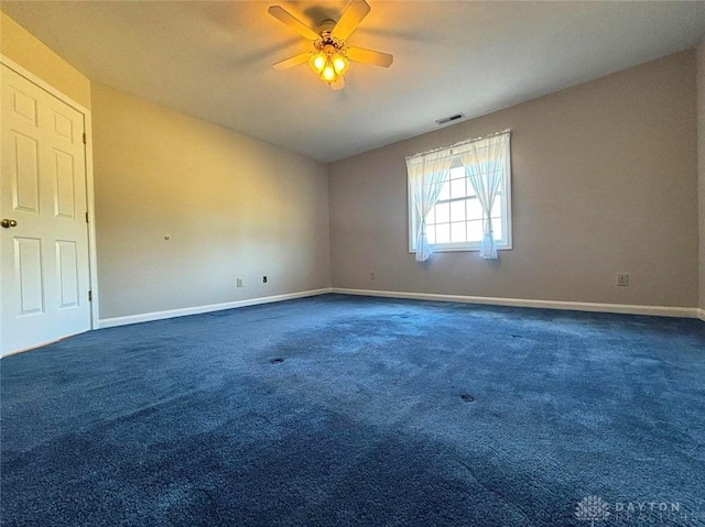 carpeted spare room with baseboards, visible vents, and a ceiling fan