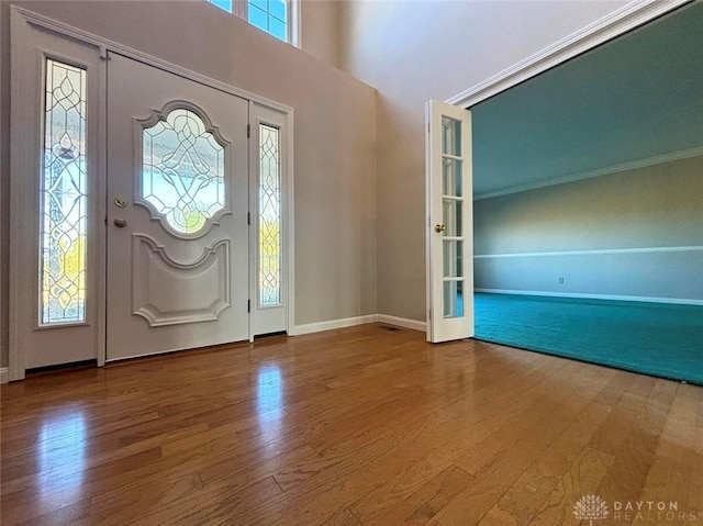 entrance foyer with crown molding, baseboards, and wood finished floors