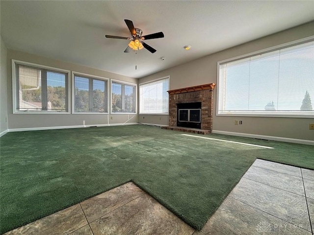 unfurnished living room with carpet floors, ceiling fan, a fireplace, and baseboards