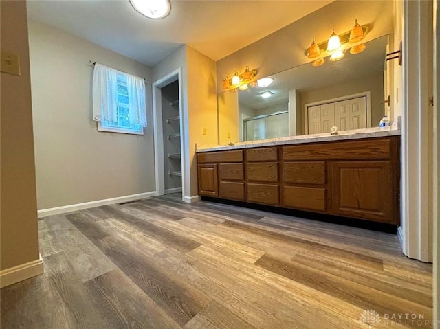 bathroom with a stall shower, vanity, baseboards, and wood finished floors