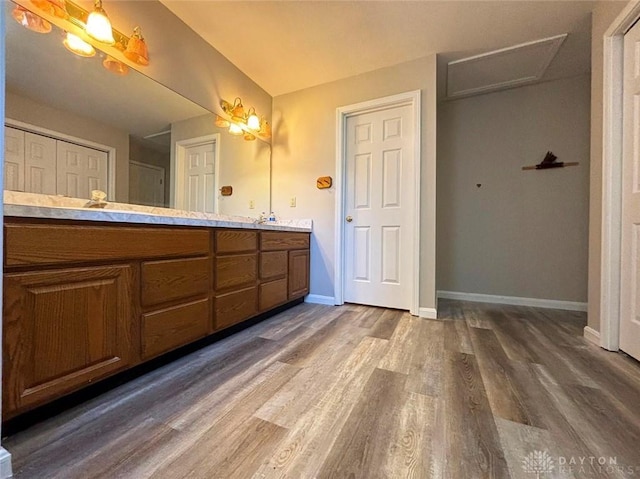 full bath featuring double vanity, baseboards, and wood finished floors