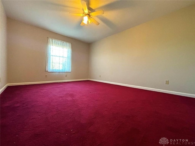 carpeted spare room with a ceiling fan and baseboards