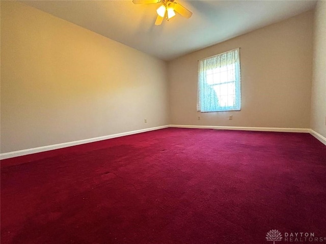 empty room with a ceiling fan, dark colored carpet, lofted ceiling, and baseboards