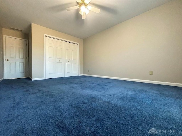 unfurnished bedroom featuring baseboards, dark carpet, ceiling fan, and a closet