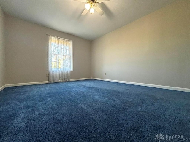 empty room featuring lofted ceiling, carpet flooring, a ceiling fan, and baseboards