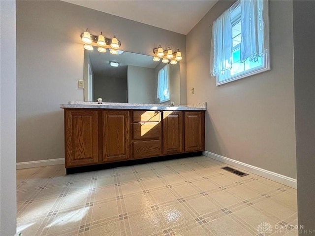 bathroom featuring double vanity, baseboards, visible vents, and a sink