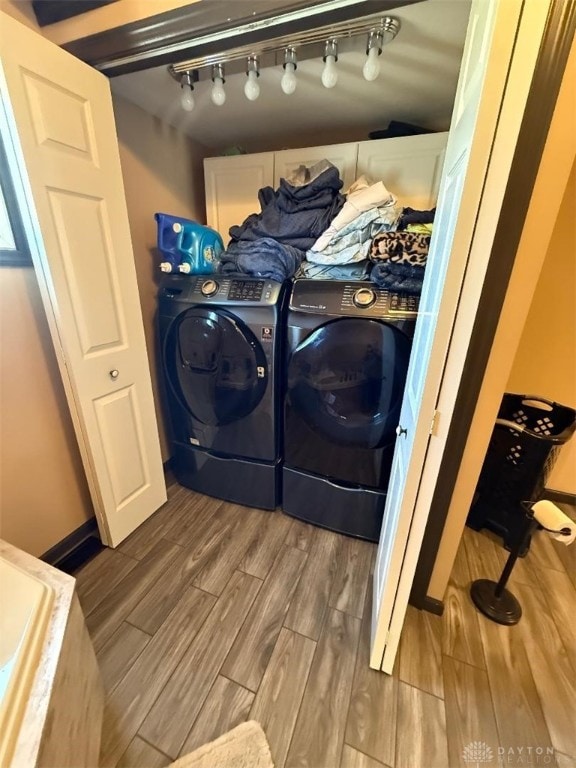 laundry room with laundry area, wood tiled floor, and washing machine and clothes dryer