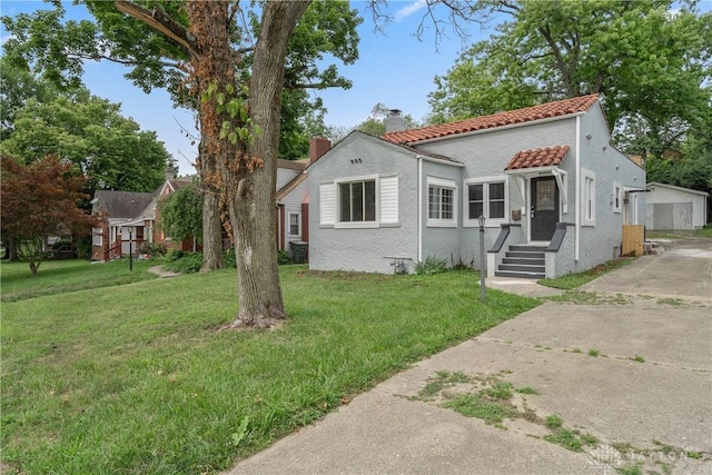 2221 Rustic Rd, Dayton, OH 45405 - view of front of property featuring a chimney, a front yard, stucco siding, and a tiled roof