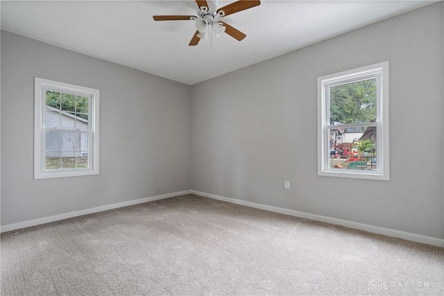 carpeted spare room featuring a ceiling fan and baseboards