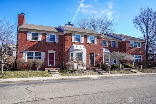 view of front of house featuring brick siding and a chimney