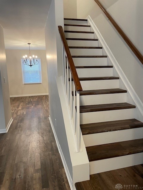 stairs with baseboards, an inviting chandelier, and wood finished floors