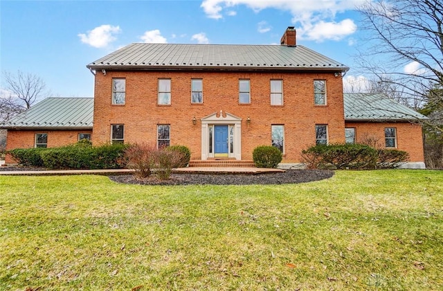 view of front of house with metal roof, brick siding, a standing seam roof, and a chimney