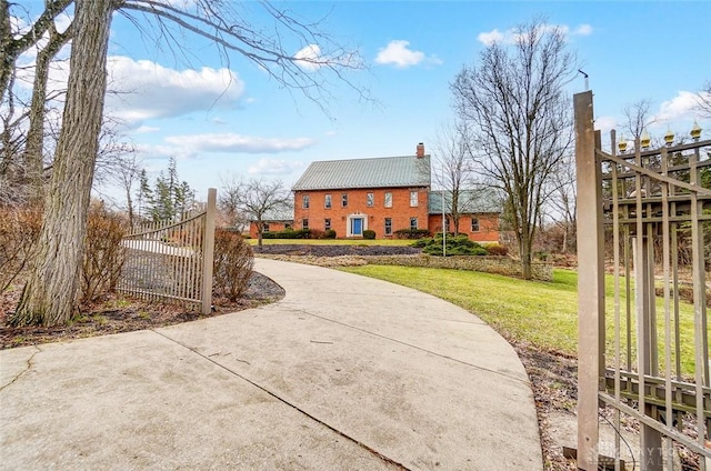 exterior space featuring brick siding, a yard, a chimney, metal roof, and fence