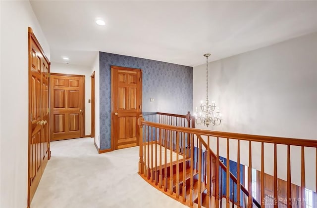 hall with a chandelier, recessed lighting, carpet flooring, an upstairs landing, and wallpapered walls