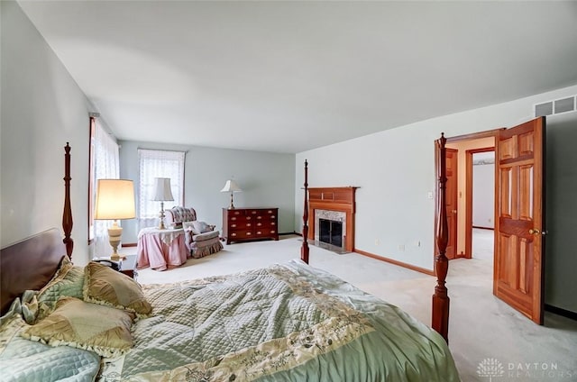 bedroom featuring light colored carpet, visible vents, a fireplace, and baseboards