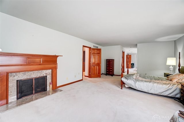 bedroom featuring visible vents, light carpet, baseboards, and a premium fireplace