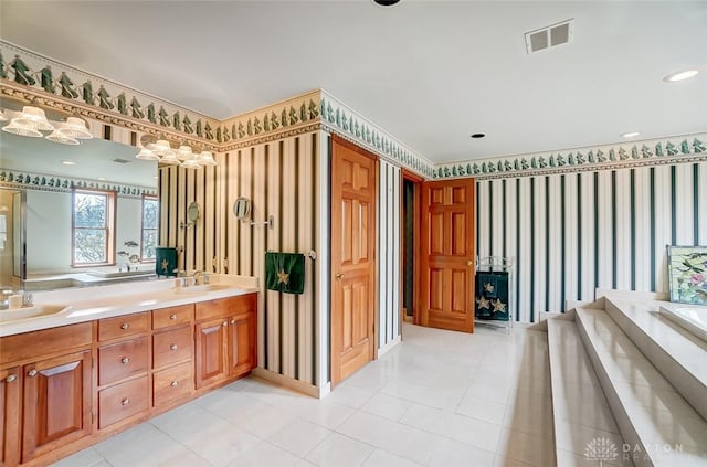 bathroom featuring a garden tub, a sink, visible vents, double vanity, and wallpapered walls