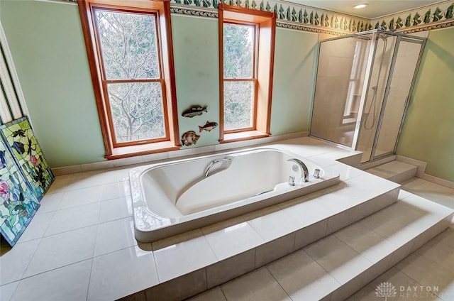 bathroom featuring a garden tub, a shower stall, and baseboards