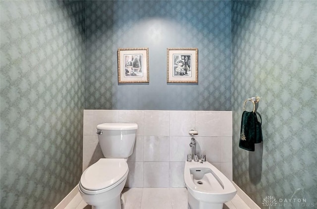 bathroom featuring tile walls, toilet, a bidet, tile patterned flooring, and wallpapered walls