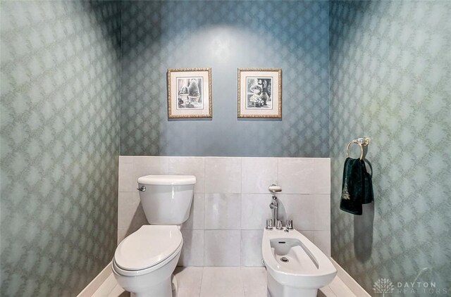 6485 Munger Rd, Dayton, OH 45459 - bathroom featuring tile walls, toilet, a bidet, tile patterned flooring, and wallpapered walls