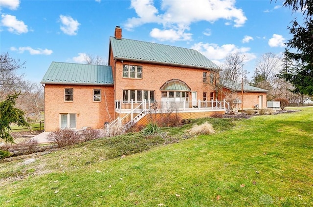 back of house featuring a standing seam roof, metal roof, stairs, a lawn, and a chimney