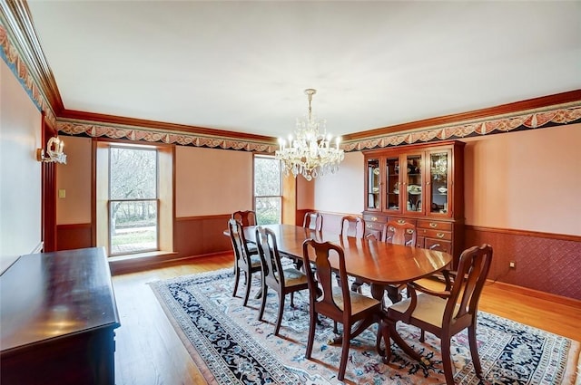 dining space featuring a wainscoted wall, ornamental molding, and wood finished floors