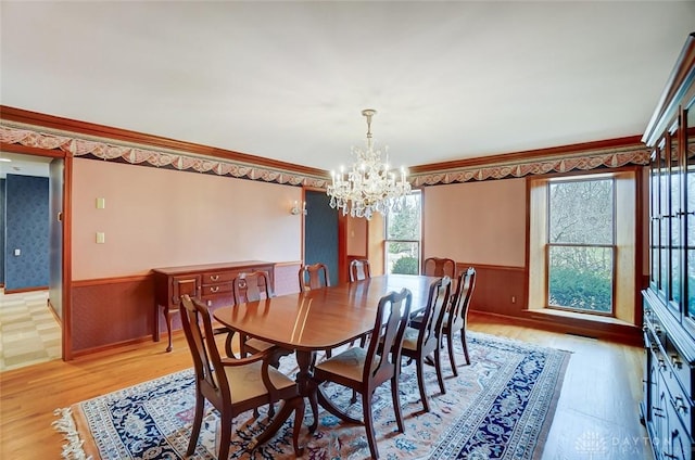 dining room with light wood-style floors, a healthy amount of sunlight, wainscoting, and crown molding